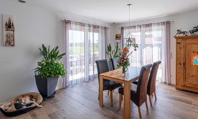 Esszimmer mit Holztisch, Lederstühlen und Terrassentür im Doppelhaus Haas D 112 D