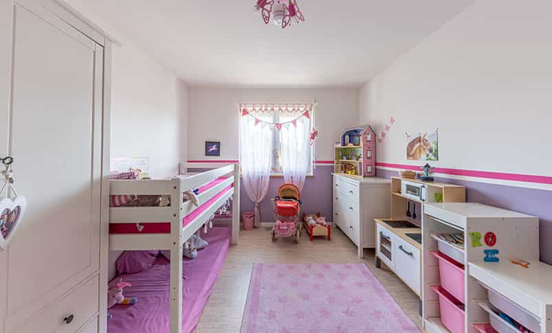 Kinderzimmer in Rosa mit Hochbett, Teppich und Spielzeug im Doppelhaus Haas D 114 B