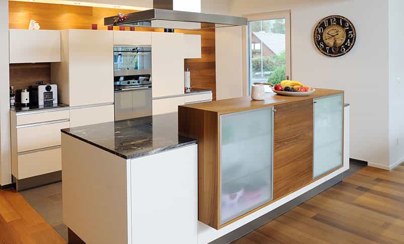Küche mit Kochinsel, Holzelementen und Wanduhr im Doppelhaus Haas D 114 B