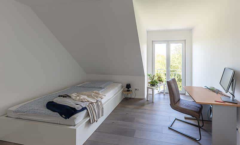 Jugendzimmer unter der Dachschräge mit Bett, Schreibtisch und Balkontür im Doppelhaus Haas D 137 B