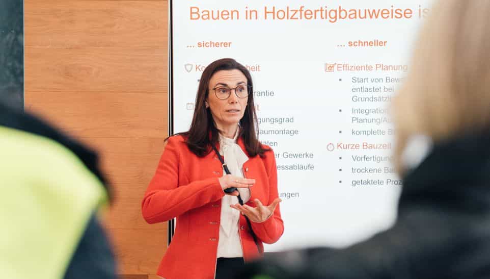Referentin im roten Blazer vor der Folie Bauen in Holzfertigbauweise bei der IHK-Gremiumssitzung