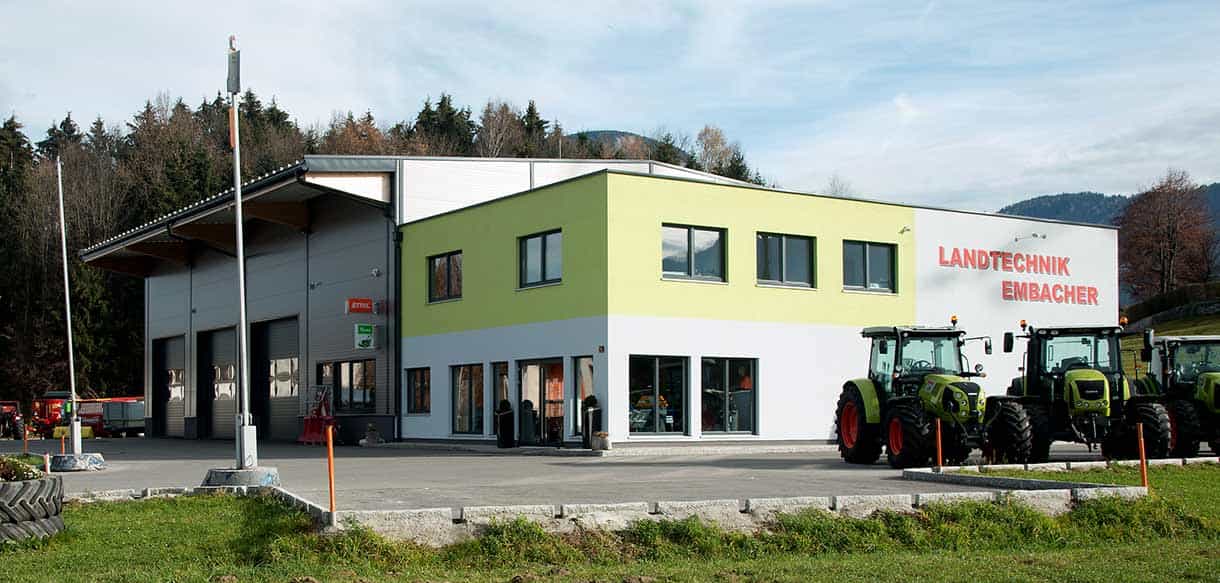 Gesamtansicht von Landtechnik Embacher mit Bürogebäude, Werkstatthalle und Traktor