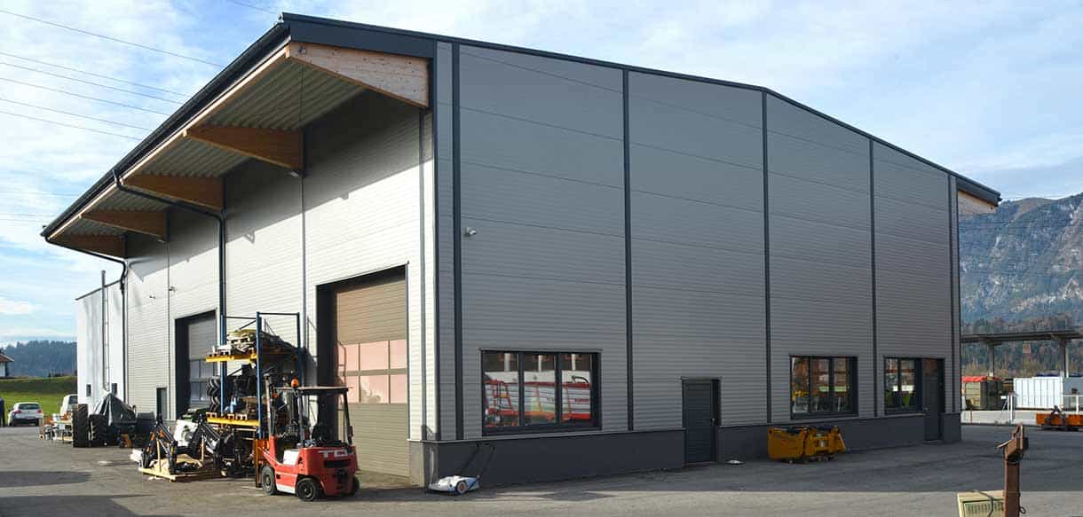 Halle von Landtechnik Embacher mit Metallfassade und Gabelstapler vor Bergkulisse