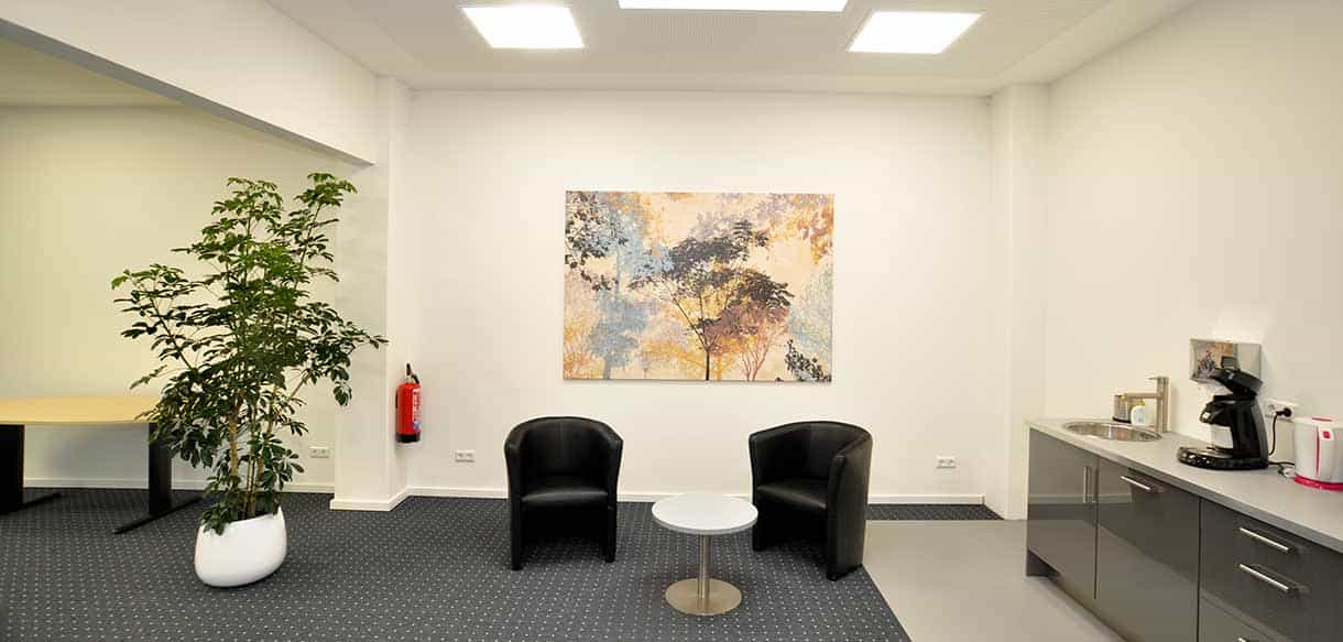 Wartebereich mit zwei schwarzen Sesseln und Sideboard im Bürogebäude von RM Bodenbeläge