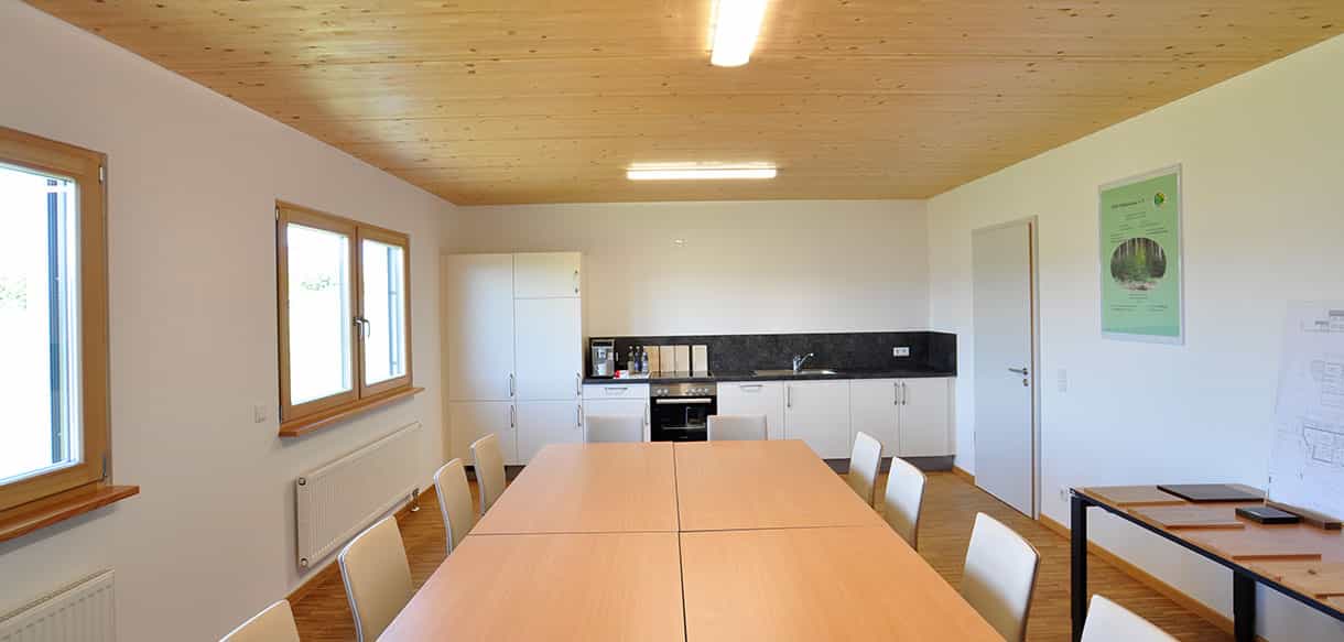 Besprechungsraum mit langem Holztisch, Küchenzeile und Holzdecke im Bürogebäude der Waldbesitzervereinigung