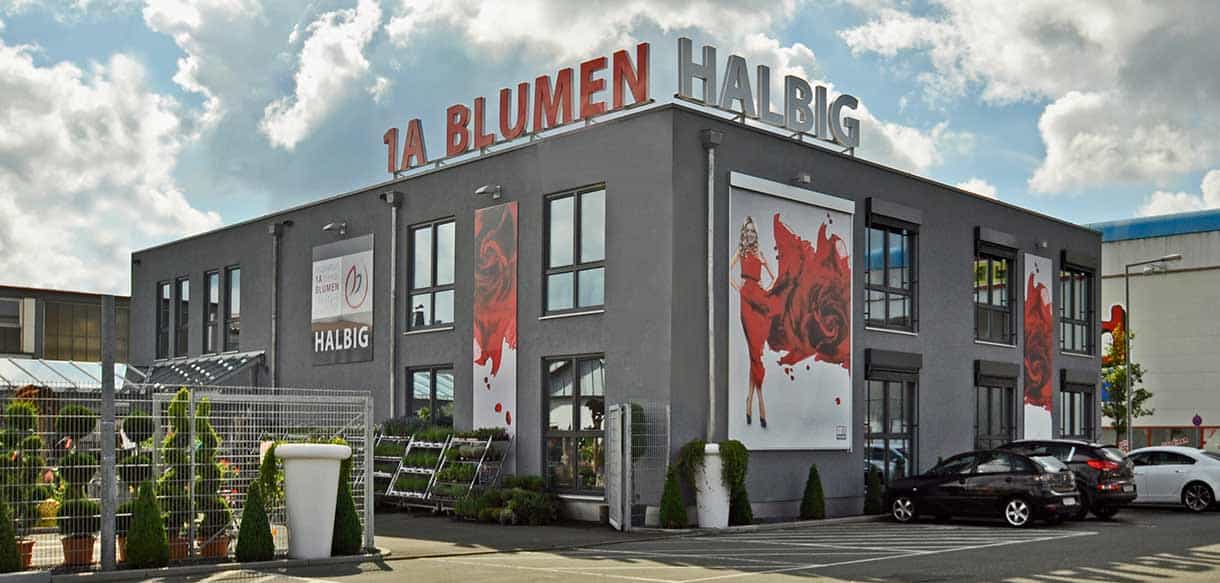 Ausstellungs- und Verkaufsgebäude von 1A Blumen Halbig mit dunkler Fassade und großem Rosenmotiv, Eckansicht