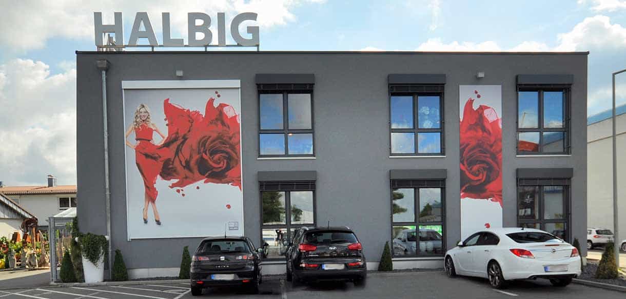 Frontansicht der Fassade von 1A Blumen Halbig mit Schriftzug und Rosenmotiv, Kundenparkplatz davor