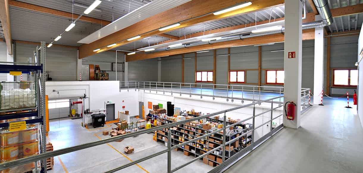 Halleninneres der Lagerhalle von Adler Lacke mit Holzbindern, Galerie und Lagerfläche