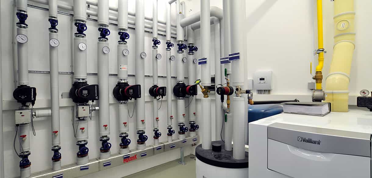 Technikraum mit Heizungsverteiler und Pumpen in der Lagerhalle von Adler Lacke, Gebäudetechnik