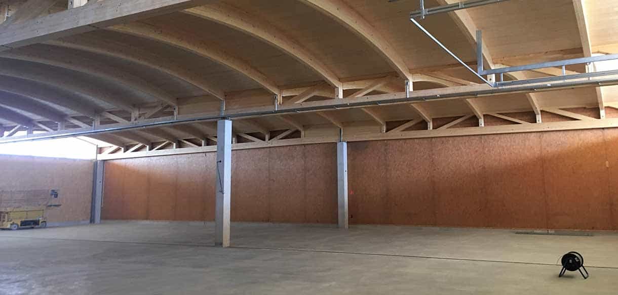 Innenansicht der Holzlagerhalle mit Bogendach und offener Seite bei G & H Scheibelhofer Reben