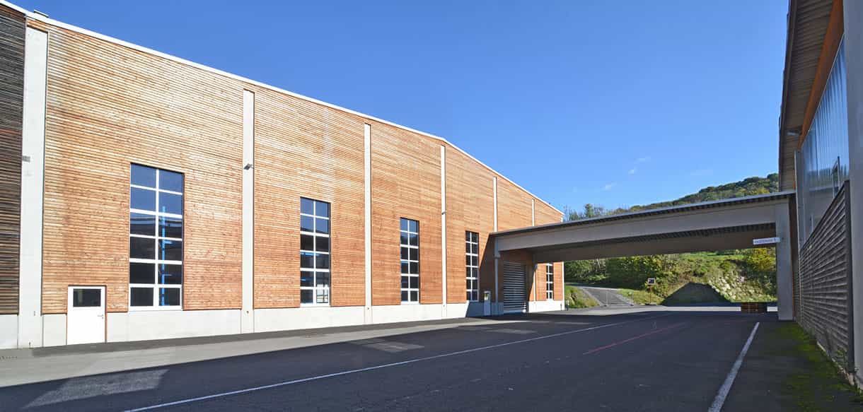 Außenansicht der Lagerhalle Scheucher Holzindustrie mit Holzfassade, Oberlichtfenstern und angebautem Vordach