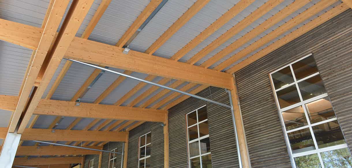 Detail der Holzkonstruktion unter dem Vordach der Lagerhalle Scheucher mit Brettschichtholzträgern und Fensterband