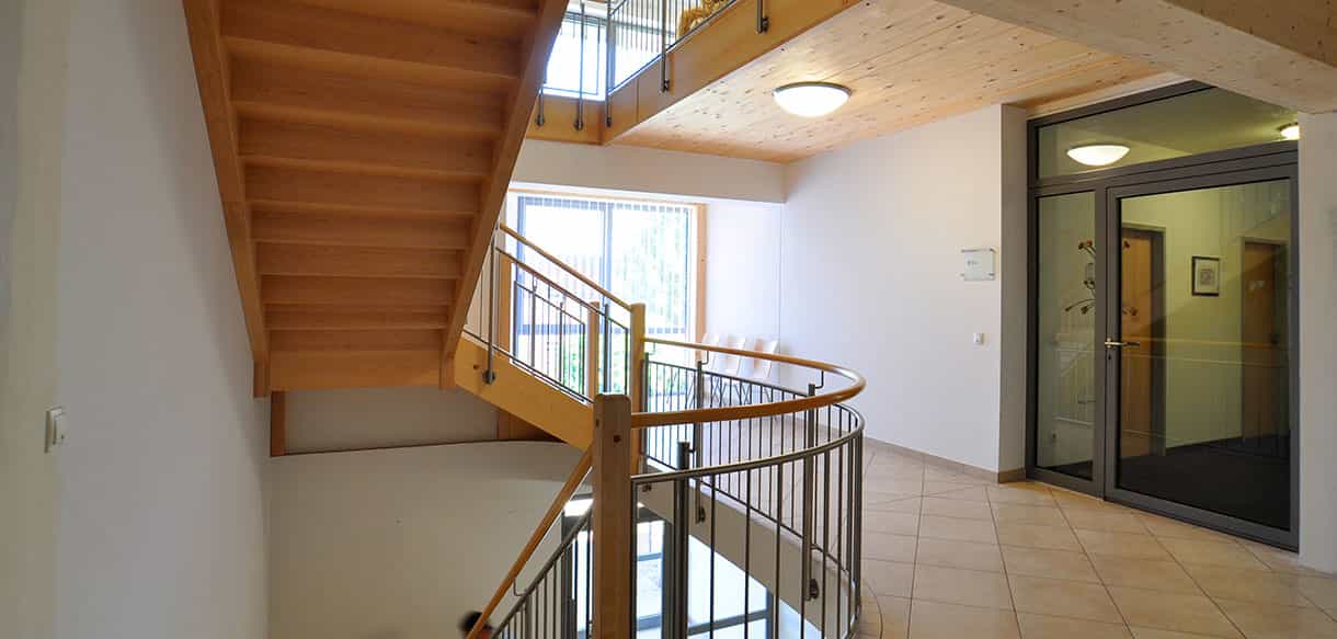 Holztreppe mit Geländer und Glastür im Bürogebäude Kaiser GmbH