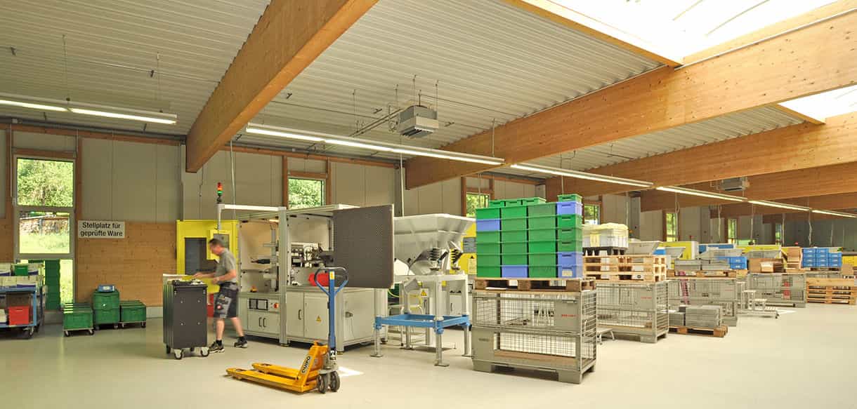 Maschinen und Mitarbeiter in der Produktionshalle des Metallwaren-Herstellers von Haas Gewerbebau