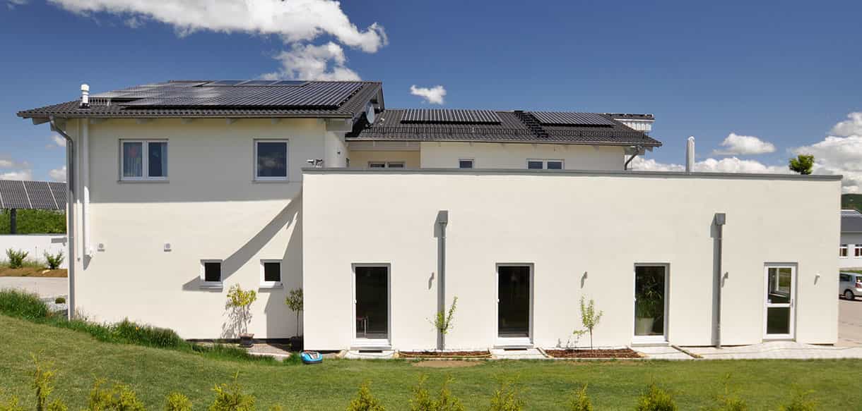 Rückansicht des Arcus Praxisgebäudes mit Photovoltaik auf dem Satteldach und Terrassentüren im Erdgeschoss