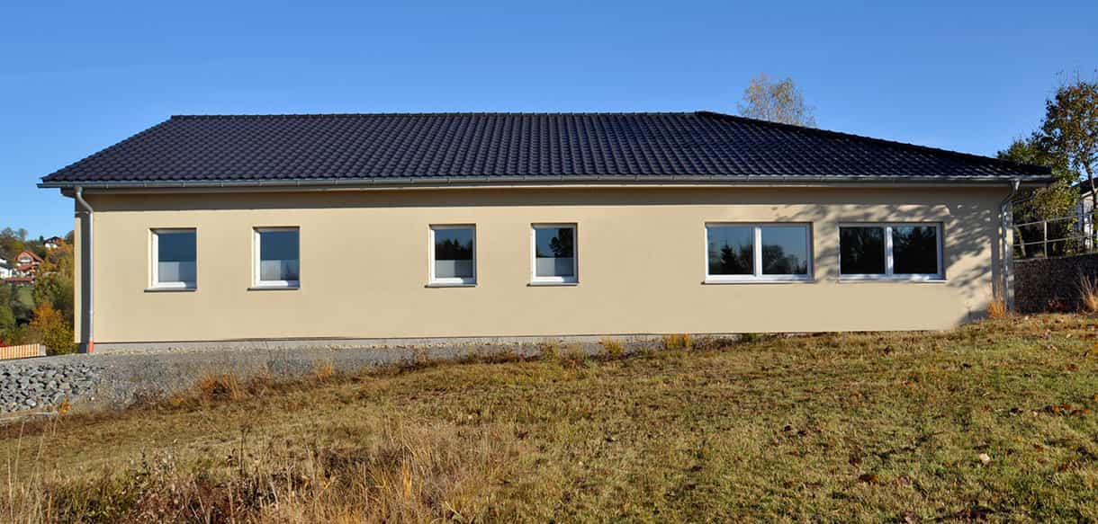 Längsseite der Physiotherapiepraxis Zielke mit Fensterreihe und Wiese davor