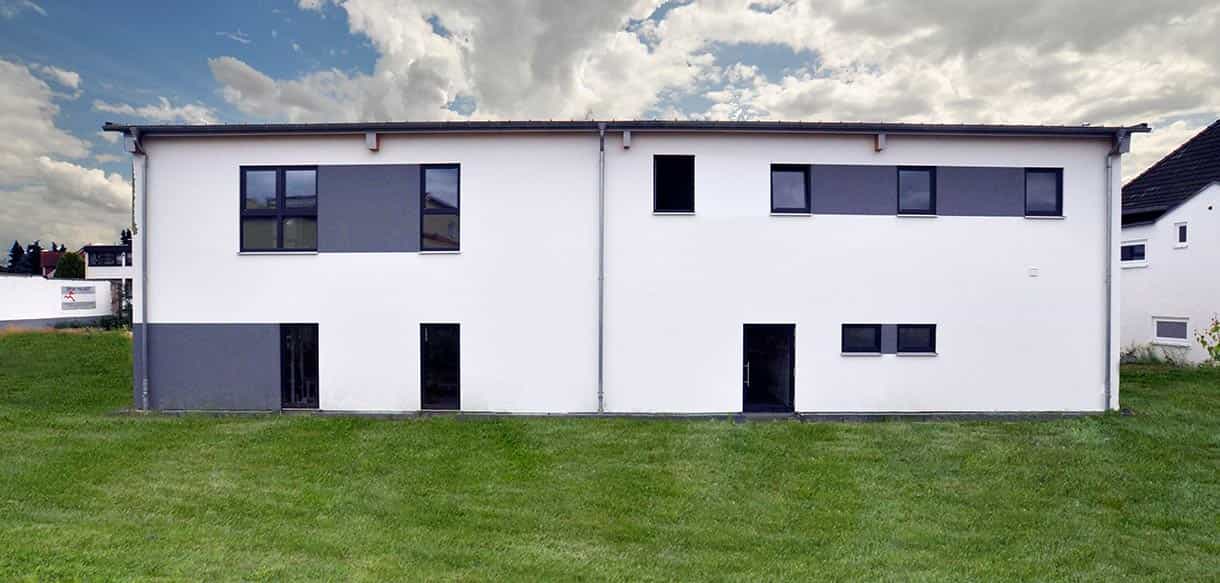 Neubau des Fitnesscenters Sportpalast Leichlingen in Systembauweise von Haas mit weißer Fassade und Rasenfläche