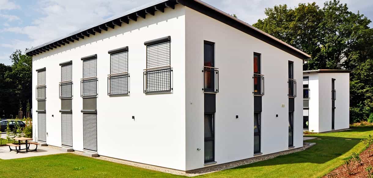 Seitenansicht des Arbeiterwohnheims Ammer mit weißer Fassade, Fensterreihen und französischen Balkonen