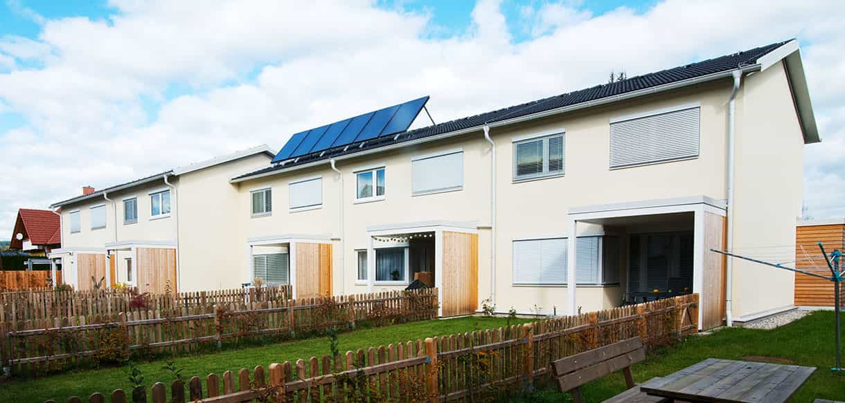 Gartenseite der Wohnungsbauanlage SGK Köflach mit Photovoltaik auf dem Dach und Holzzäunen