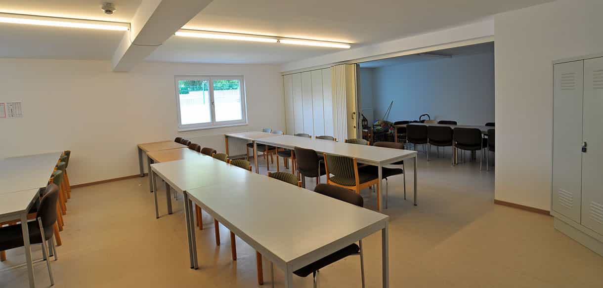 Aufenthaltsraum mit langen Tischreihen und Fenster im Wohnheim mit 29 Zimmern in Neunkirchen am Sand