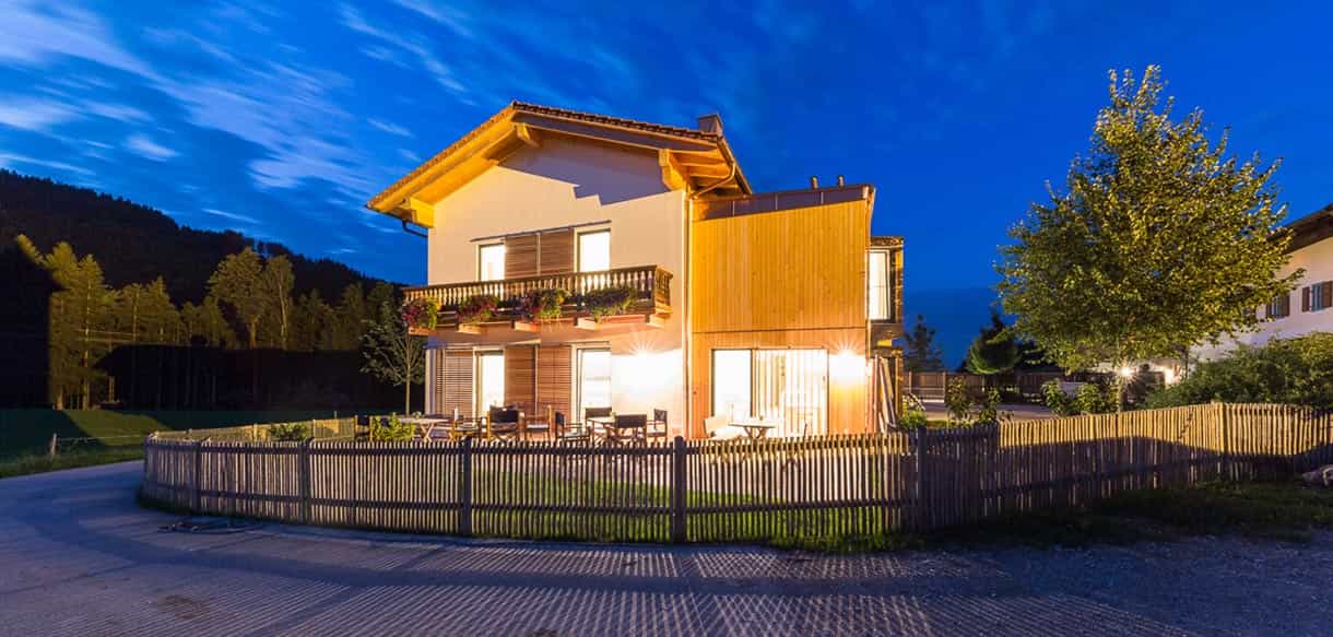 Pension Moarhof am Samberg in der Abenddämmerung mit beleuchteter Holzfassade und Gartenzaun