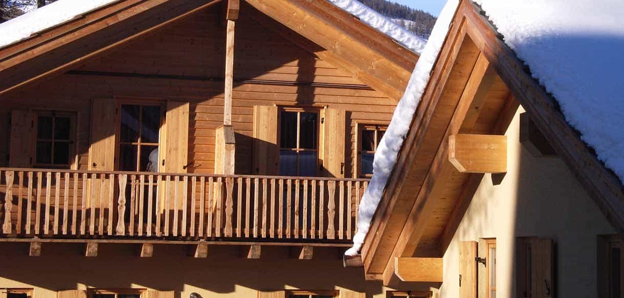 Detail von Holzbalkon und Dachgiebel eines Chalets in der Ferienwohnanlage Pragelato