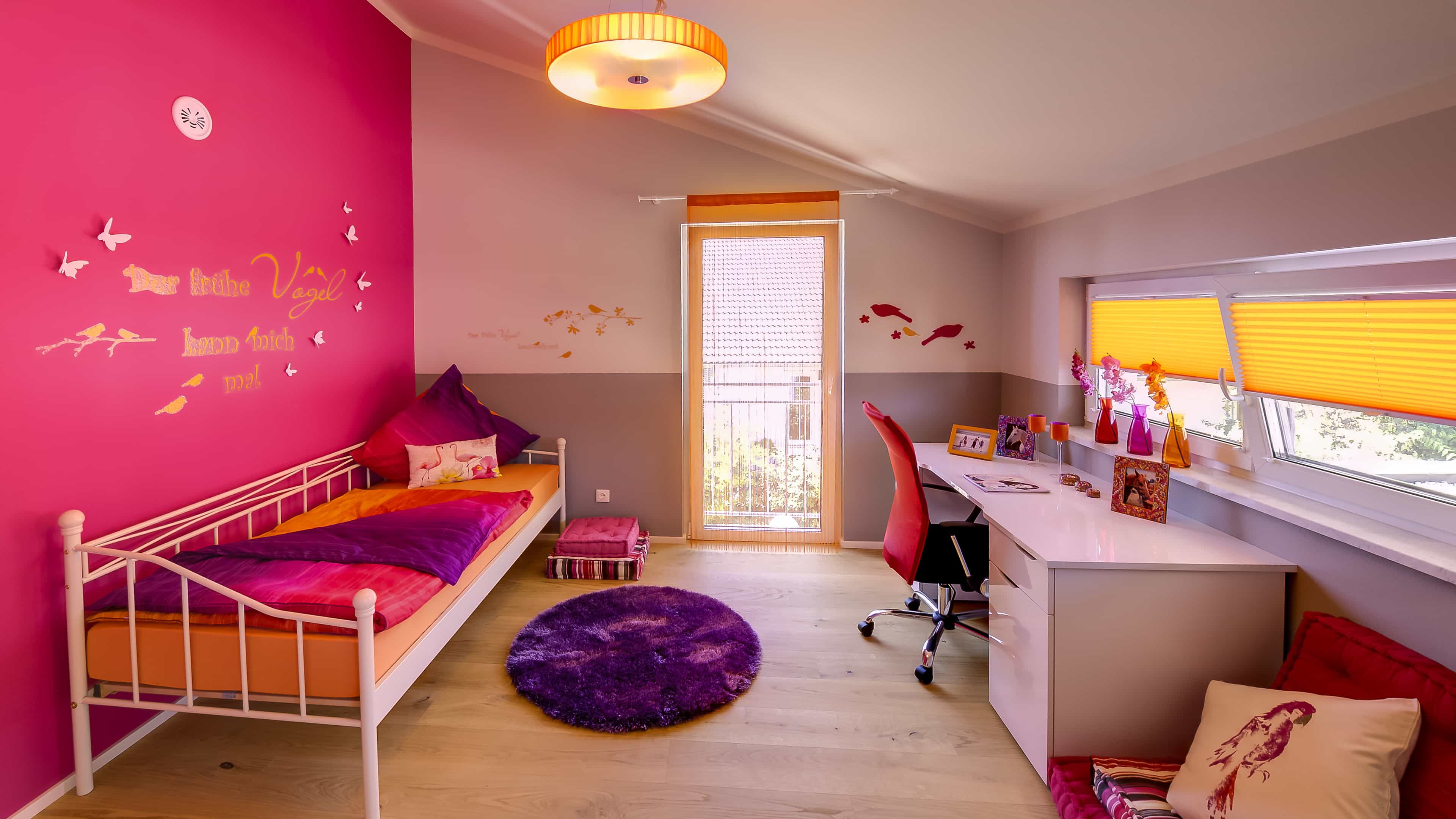 Kinderzimmer mit pinker Wand, weißem Metallbett und Schreibtisch im Musterhaus Haas MH Mannheim J 159