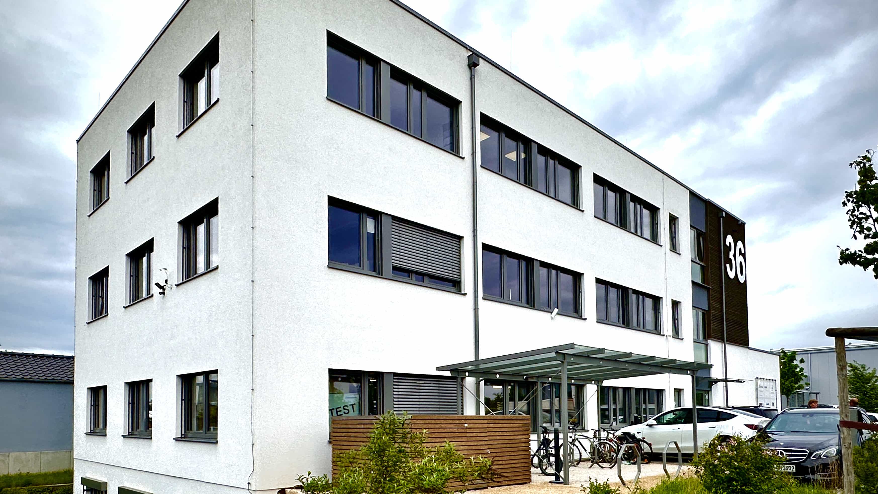 Gebäudeecke des Bürogebäudes LXinstruments mit dunklem Fassadenband und Vordach
