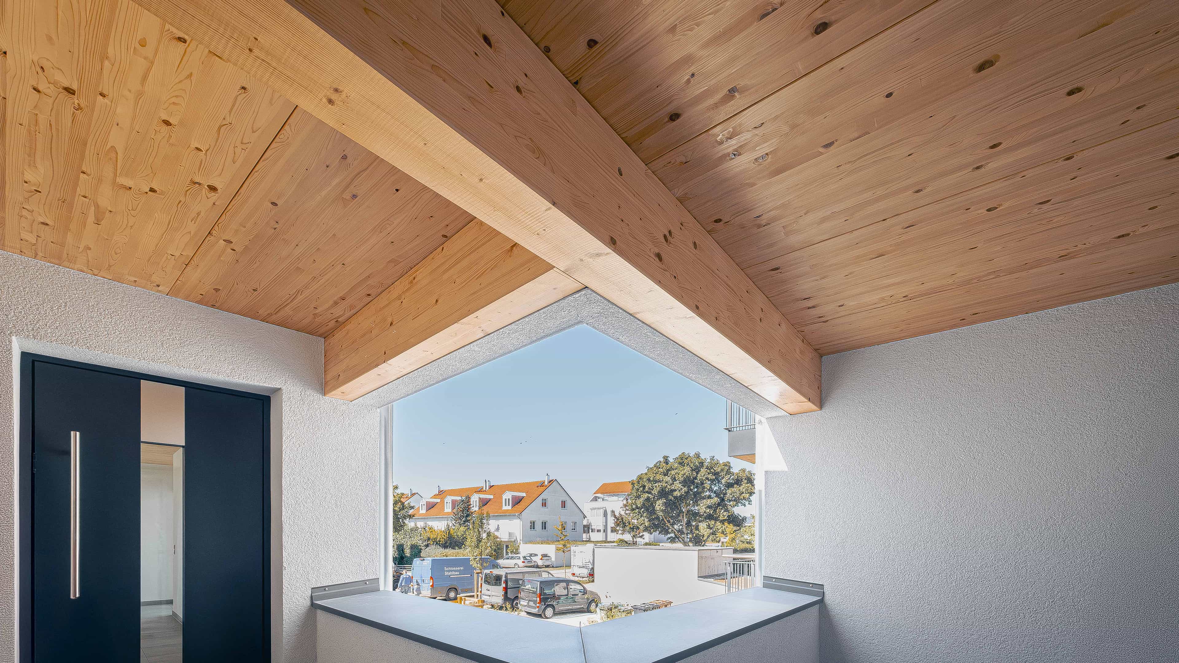 Loggia mit Holzdach, dunkler Haustür und Ausblick auf Eching