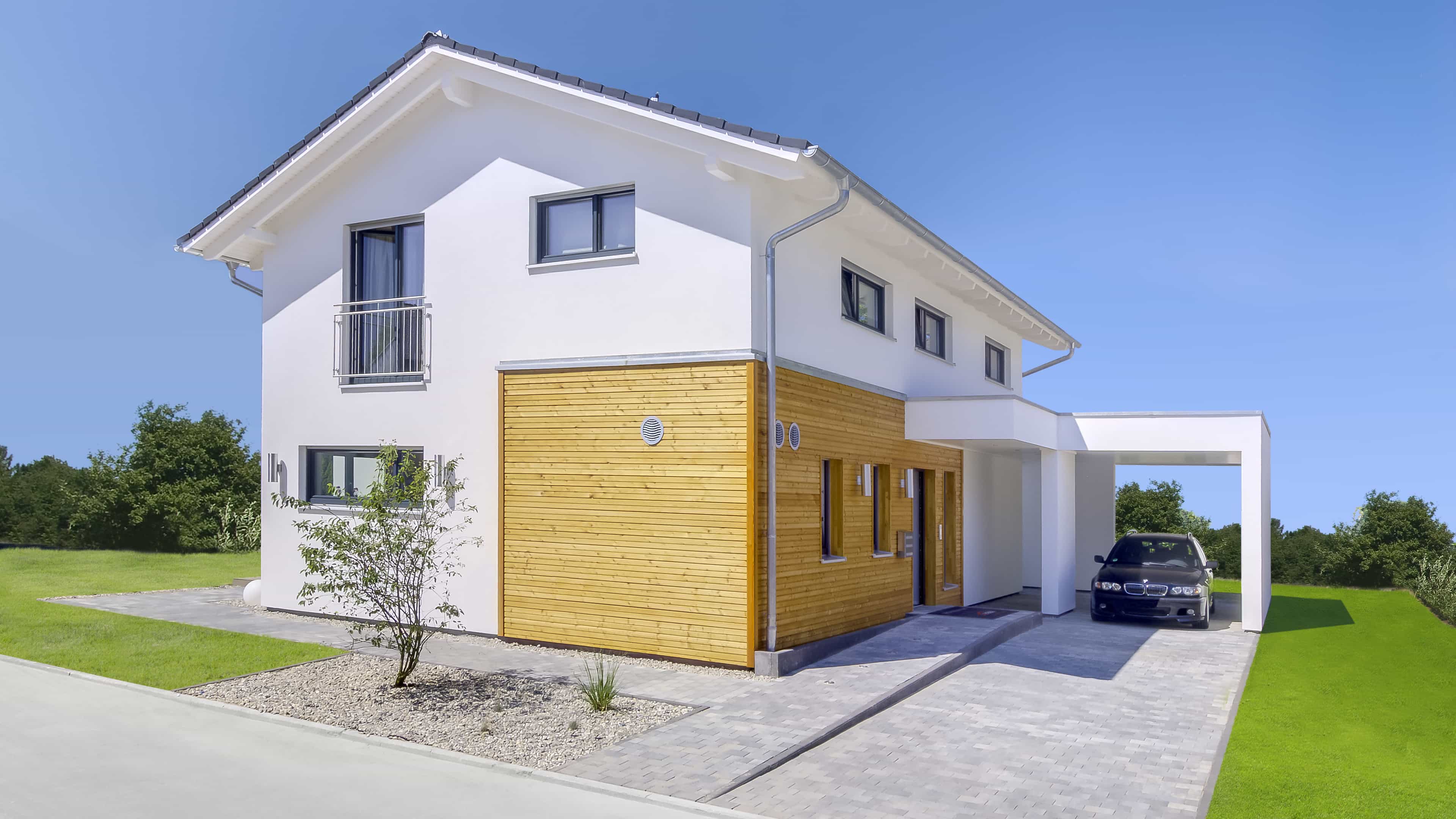 Hofansicht des Musterhauses Haas MH Mannheim J 159 mit Holzelement und Carport bei Tag
