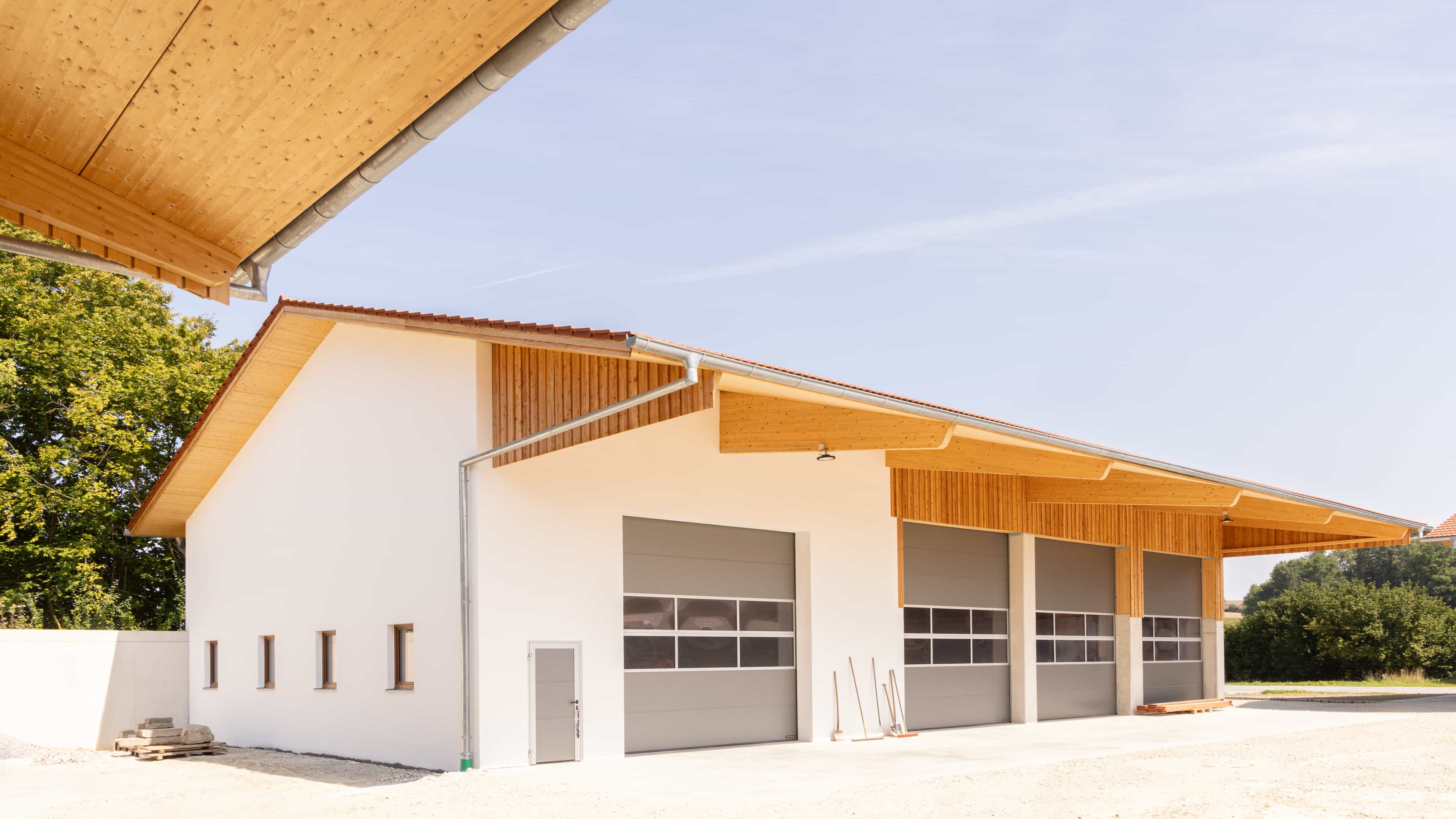 Giebelseite der Maschinenhalle in Wang mit Holzfassade, Sektionaltoren und Vordach