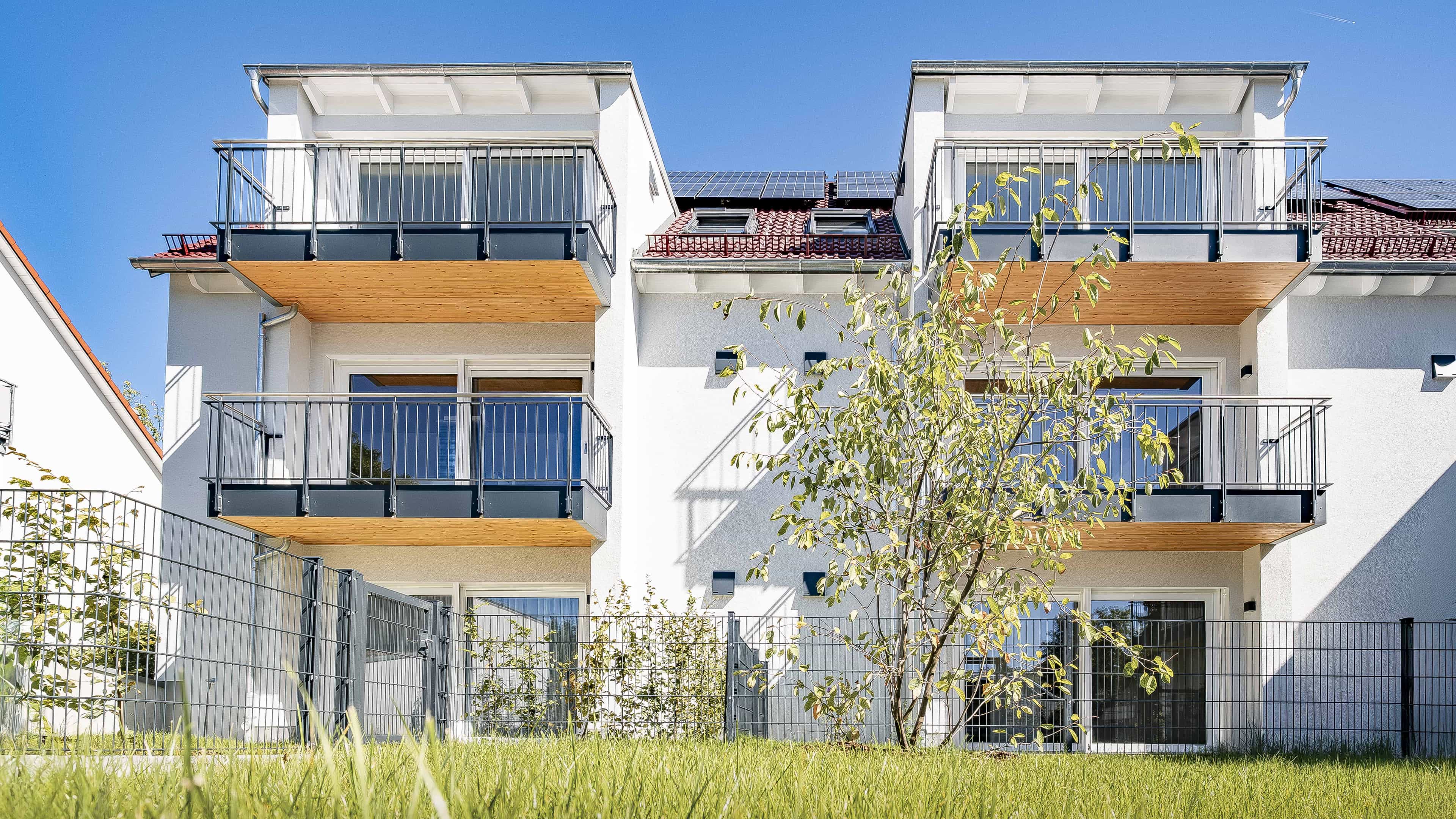 Gartenseite des Mehrfamilienhauses in Eching mit Balkonen und Wiese