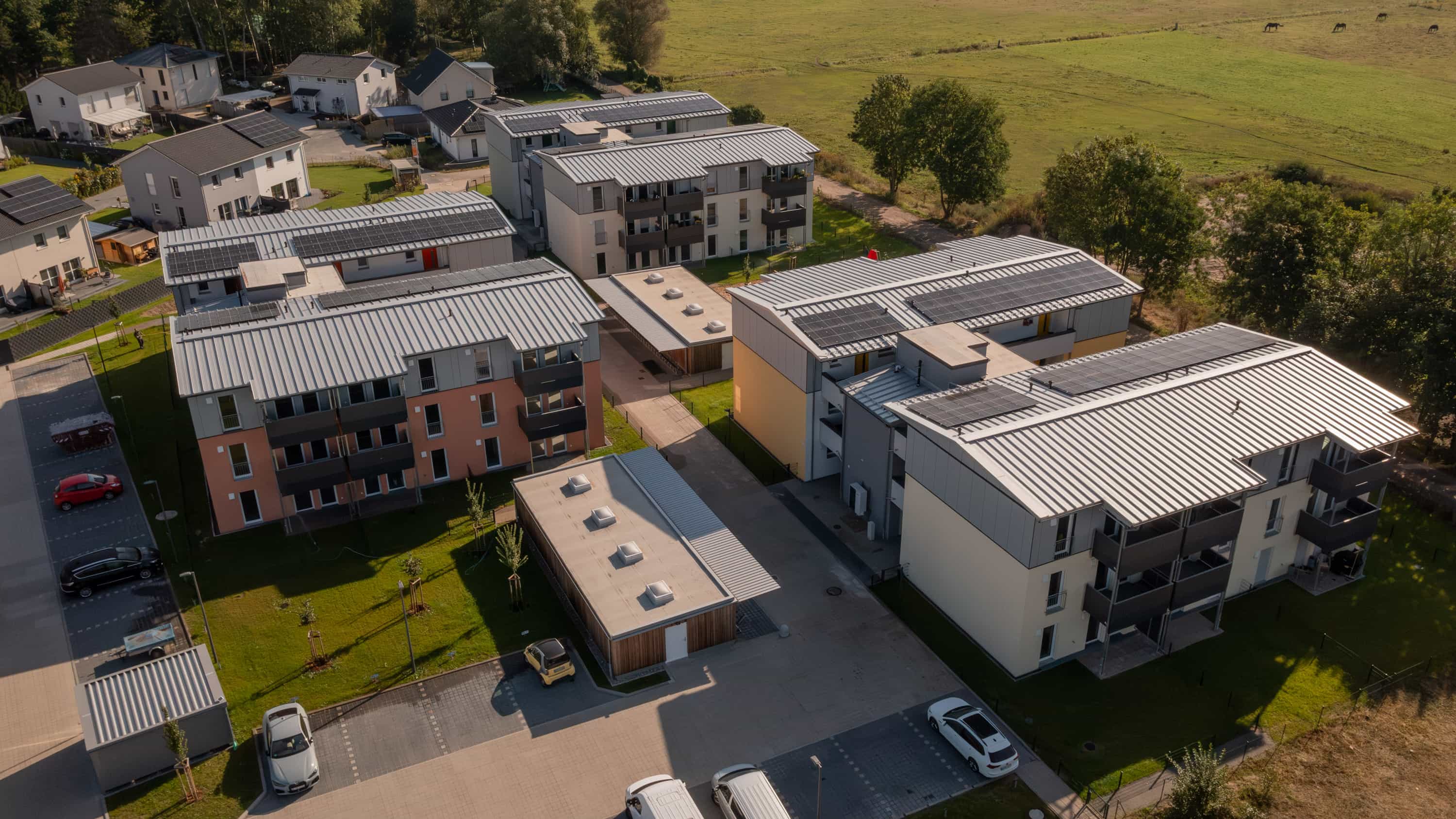 Luftaufnahme der Mehrfamilienhäuser Zum Glück Bötzow mit Photovoltaikdächern bei Berlin