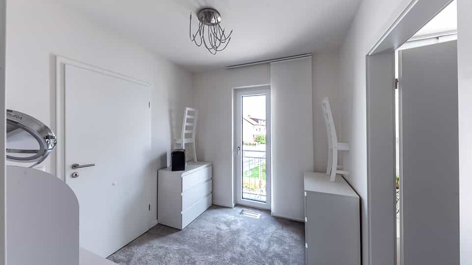 Ankleidezimmer mit weißer Kommode und Balkontür im selbst geplanten Haas Fertighaus der Familie Schmid