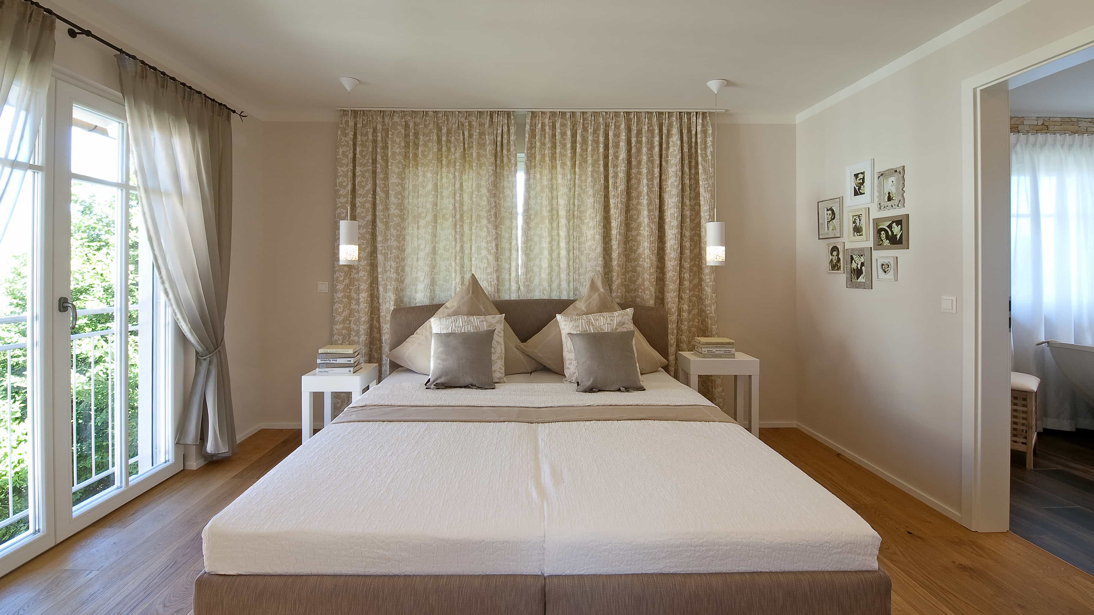 Helles Schlafzimmer mit Doppelbett, Vorhängen und Gartenfenstern im Musterhaus Haas MH Poing 187