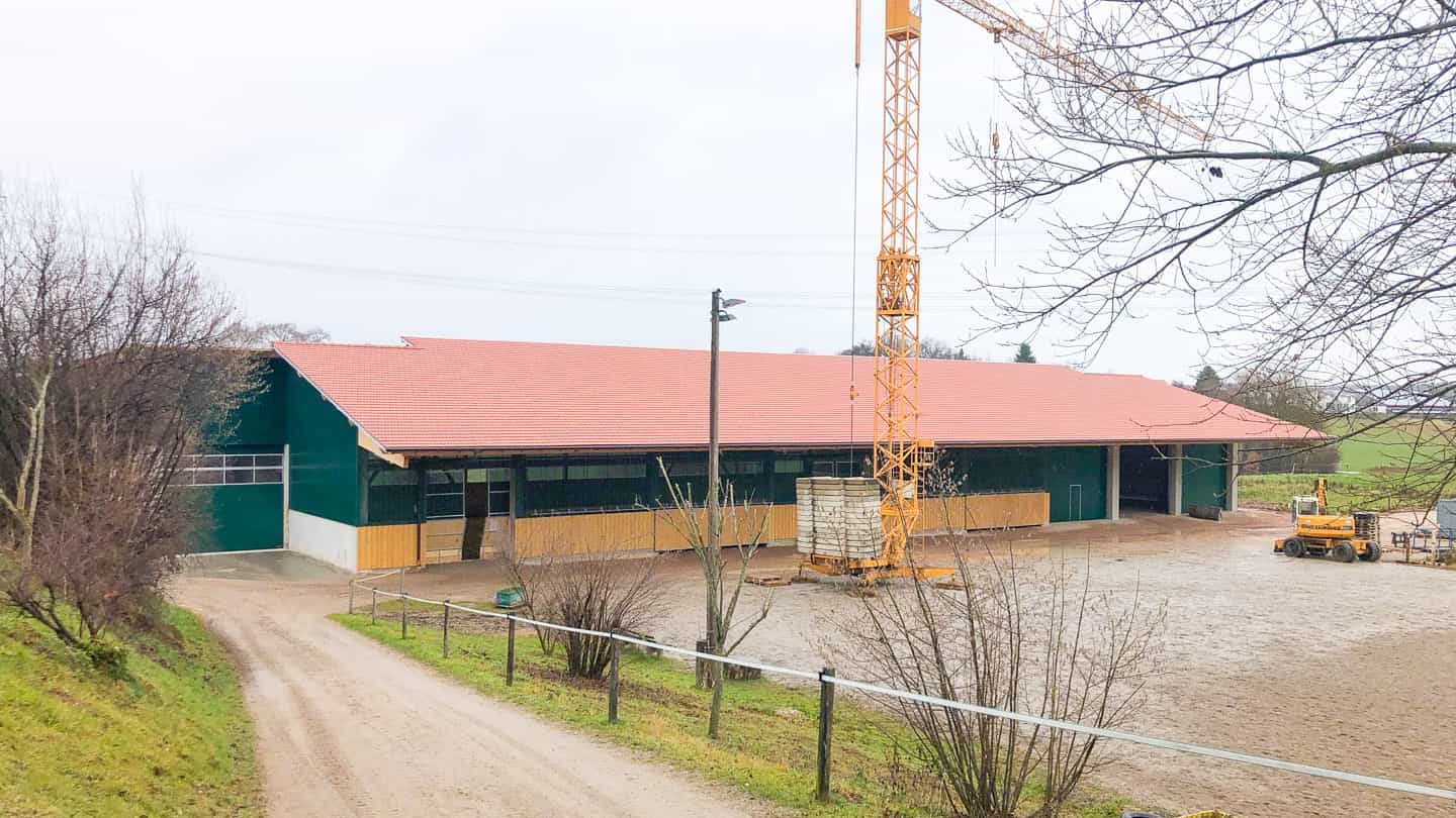 Reitanlage in Kleinberghofen mit rotem Dach und Baukran während der Bauphase