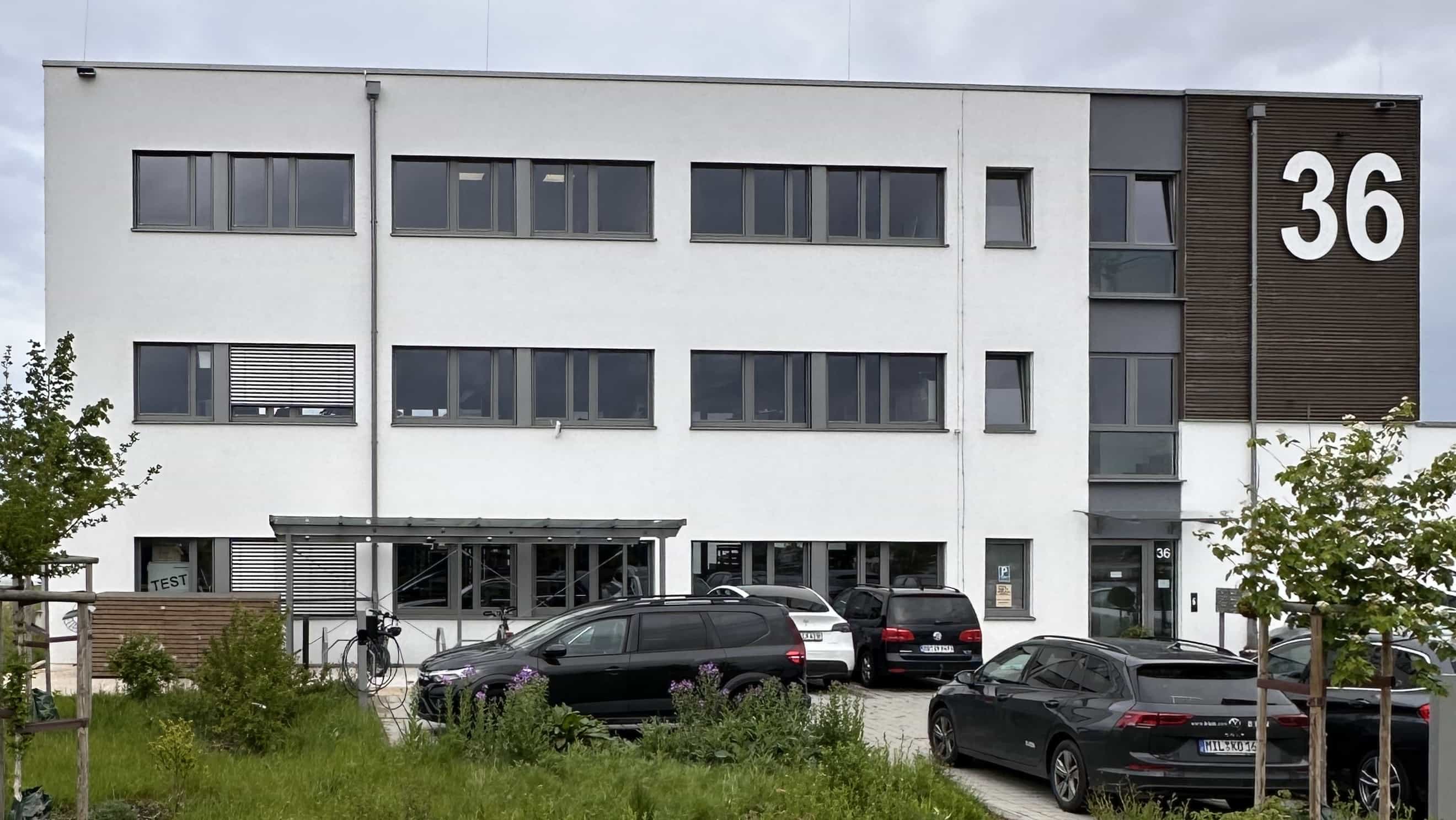 Frontansicht des Bürogebäudes LXinstruments mit Eingang, Vordach und Parkplatz