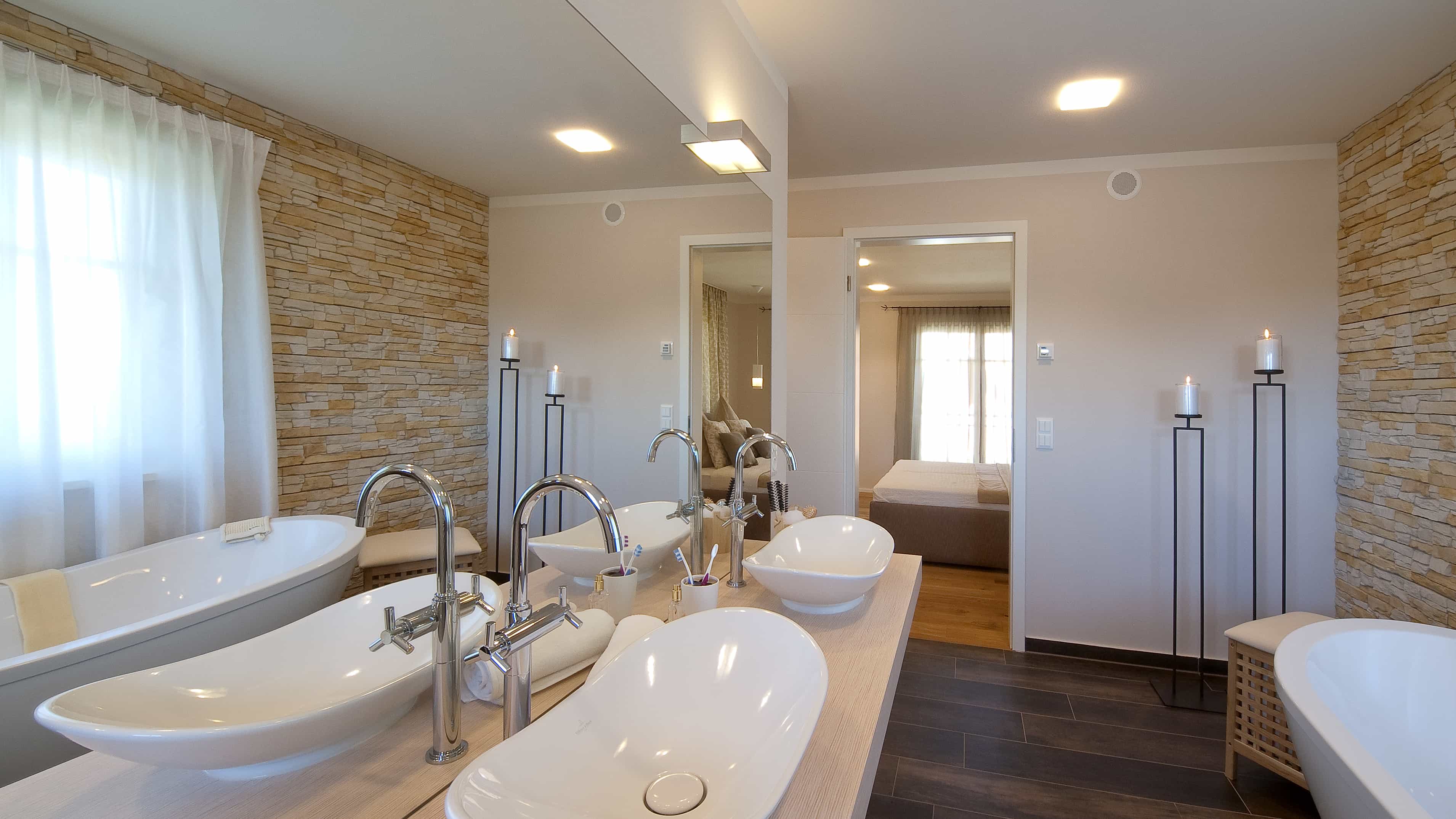 Badezimmer mit zwei Aufsatzwaschbecken, Natursteinwand und Wanne im Musterhaus Haas MH Poing 187