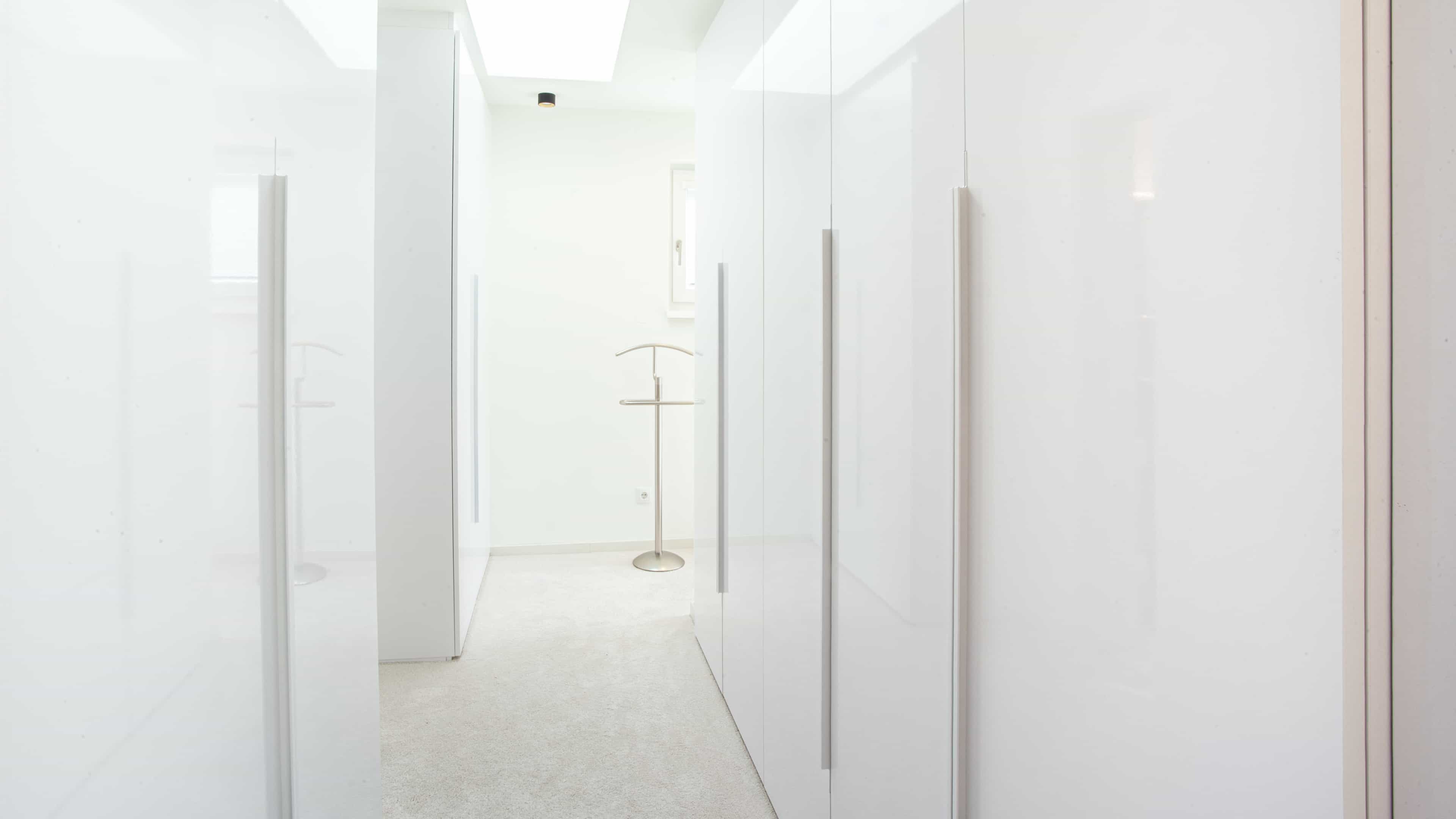 Ankleidezimmer mit weißen Hochglanzschränken im modernen Haas Ferienhaus