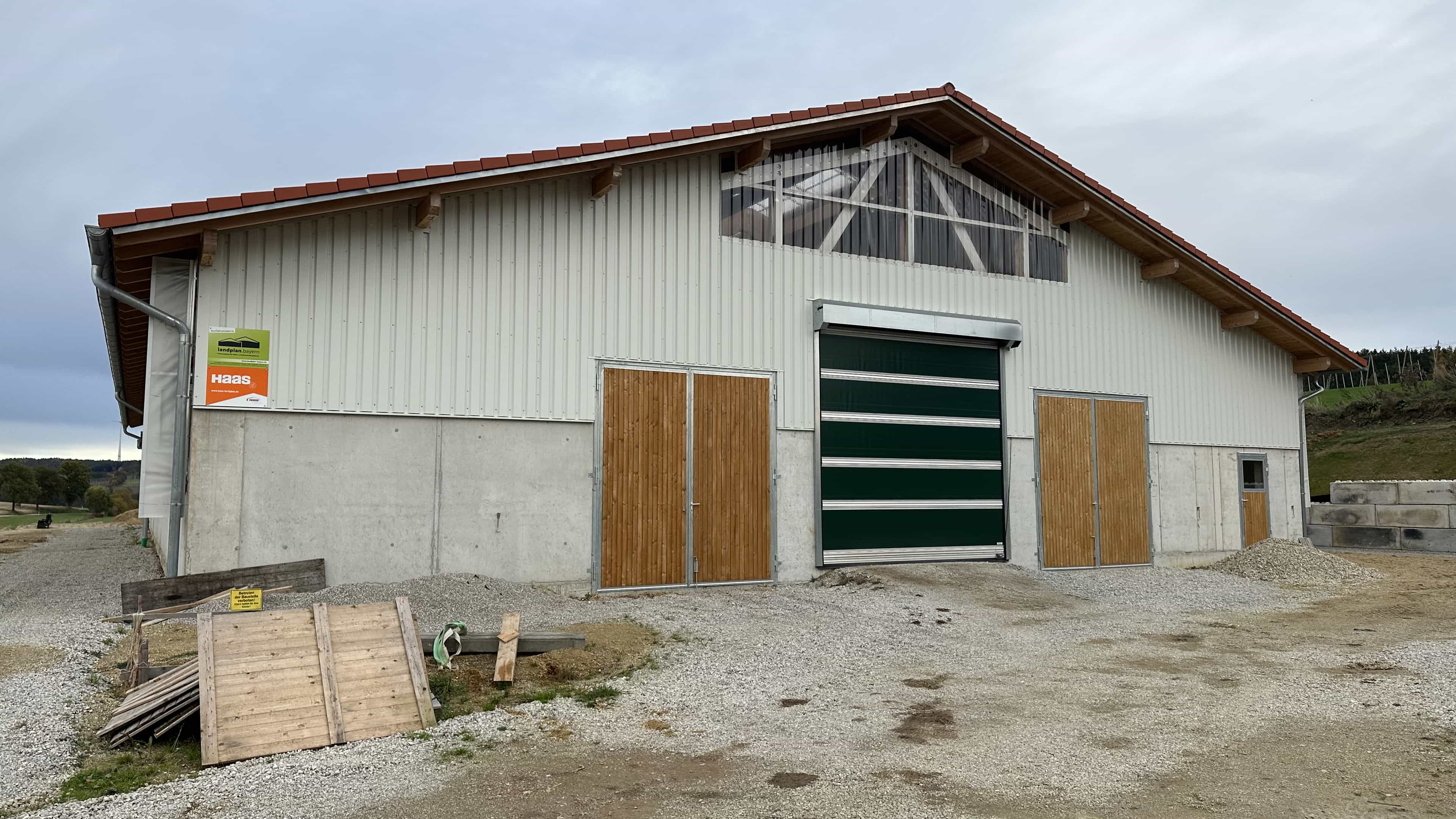 Giebelseite des Bullenmaststalls mit grünem Tor und Holztüren