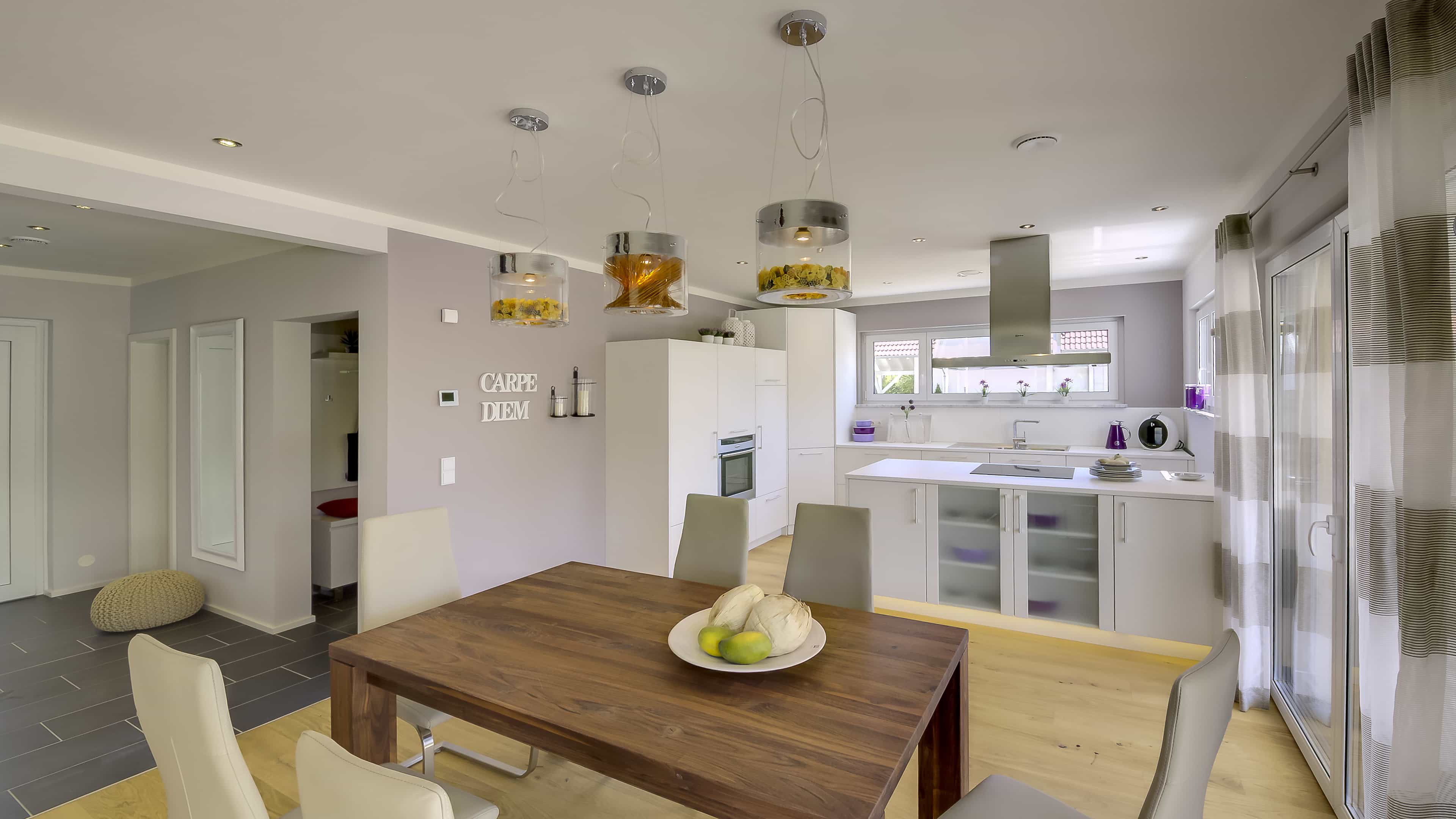 Esszimmer mit Holztisch und offener weißer Küche im Musterhaus Haas MH Mannheim J 159