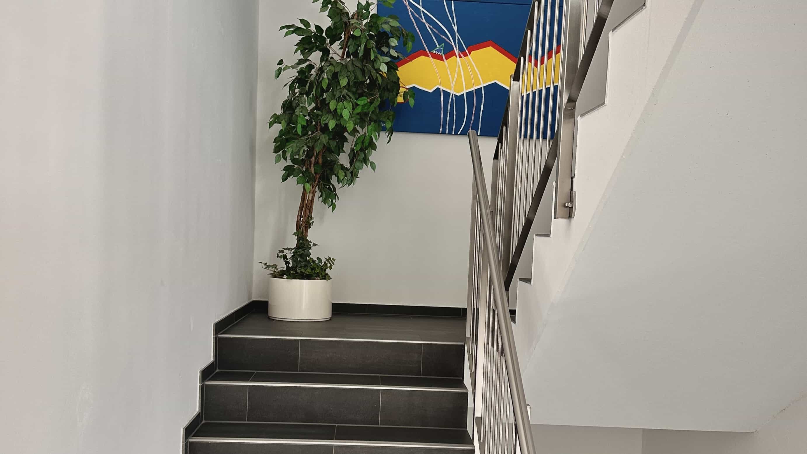 Treppenhaus mit Wandbild und Pflanze im Bürogebäude der LXinstruments GmbH