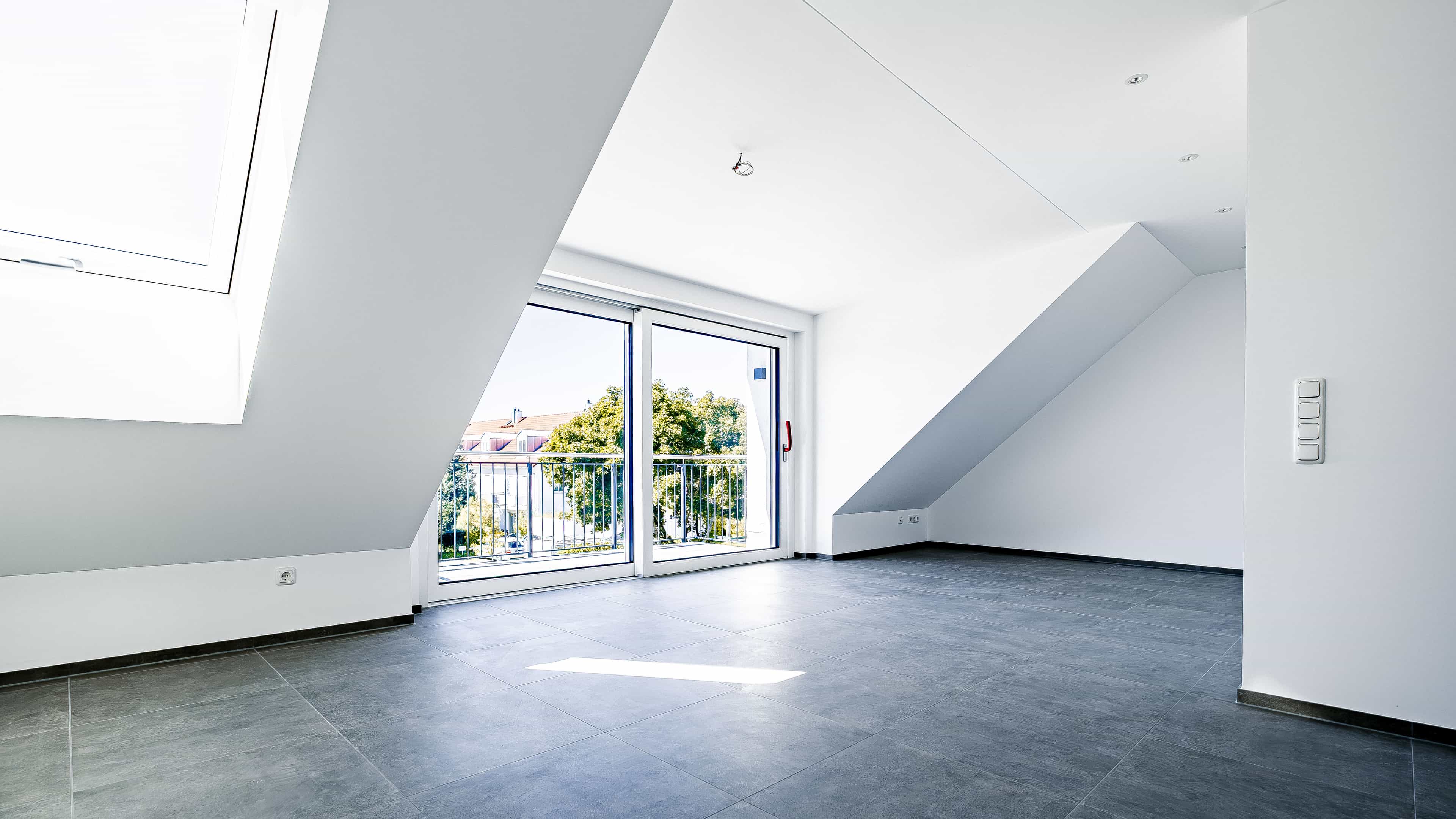 Leere Dachgeschosswohnung mit Dachschräge und Balkontür im Wohnprojekt Eching